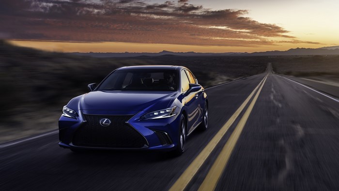 Blue Lexus ES F Sport driving on a desert highway at sunset