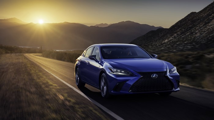 Blue Lexus ES F Sport driving on a mountain road at sunset