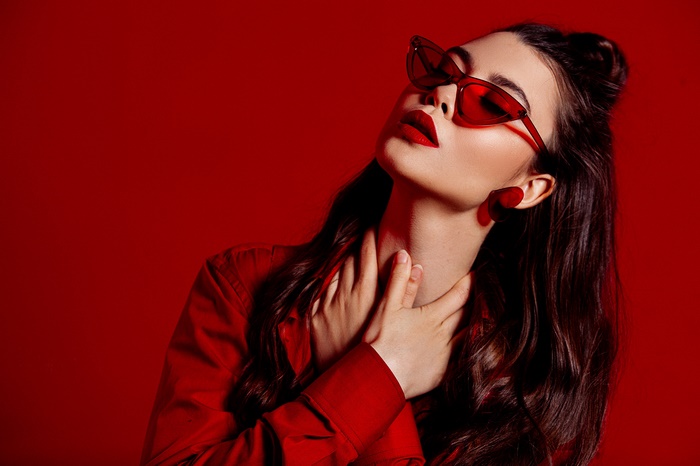 Woman with black hair wearing red sunglasses and lipstick