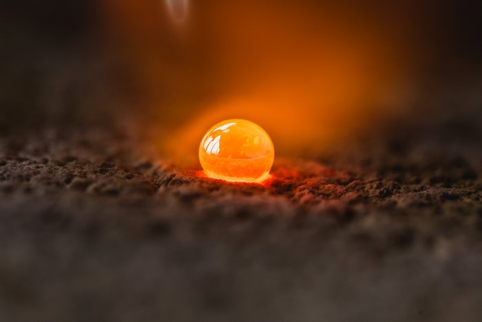 Hot molten metal ball glowing on dark surface