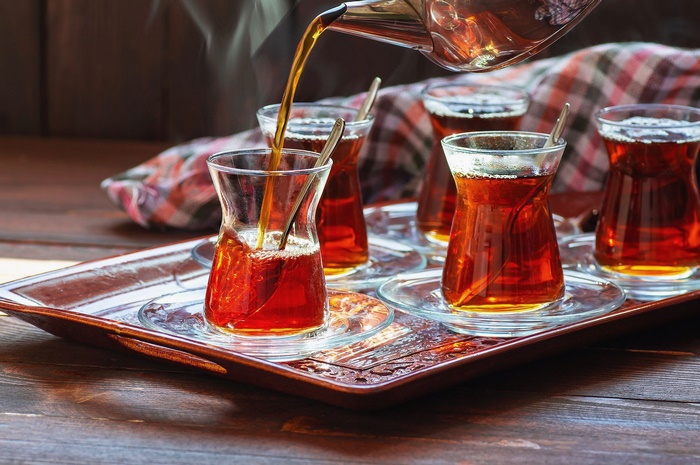 Tea being poured into traditional Turkish tea glasses