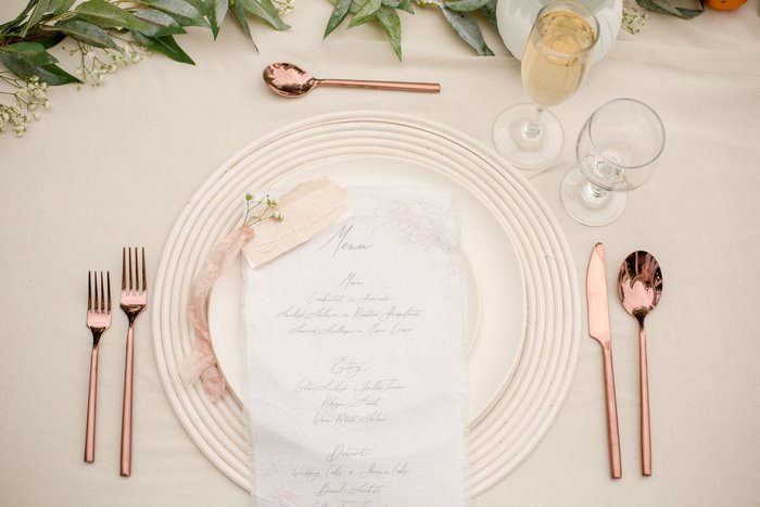 Wedding table setting with menu and rose gold cutlery