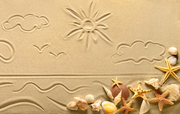 Sand drawings of sun, clouds, birds, and seashells on a beach