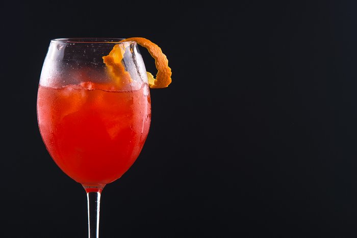 Close up of a red cocktail with orange rind