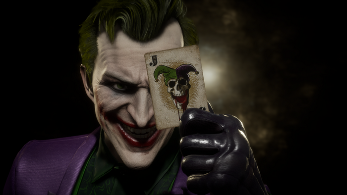 The Joker holds a playing card in front of his face
