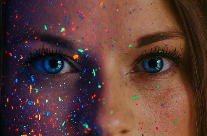 Close-up of a woman's face with neon paint splatters