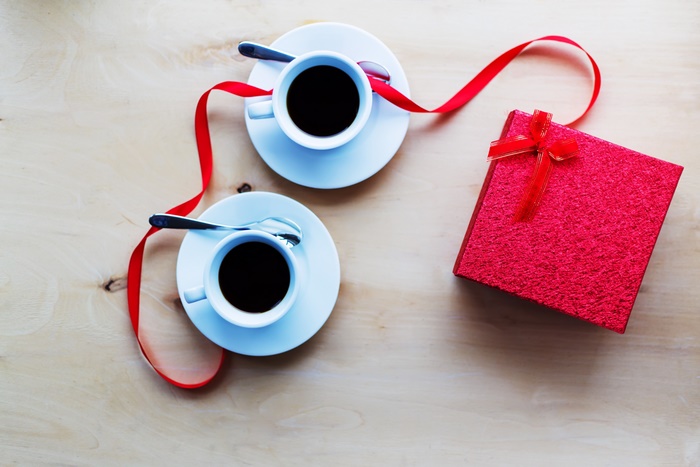 Two cups of coffee and a gift with red ribbon