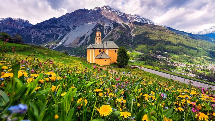 Yellow church in a mountain landscape with wildflowers