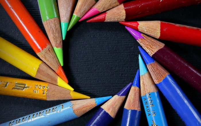 Colored pencils arranged in a circle on a black surface