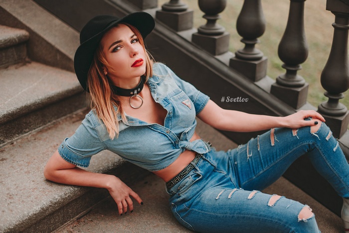 Woman in denim outfit and hat sitting on stairs