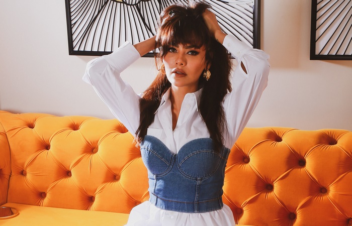 Esha Gupta posing on an orange couch