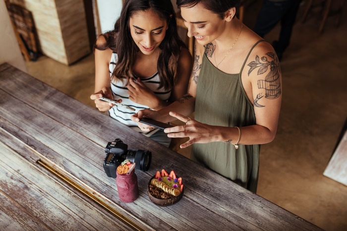 Two women taking a photo of food with a camera and phone