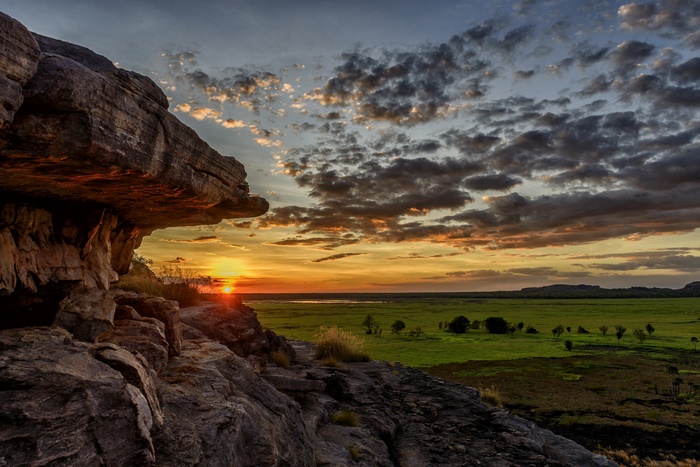 Rock formation overlooking a grassy plain at sunset