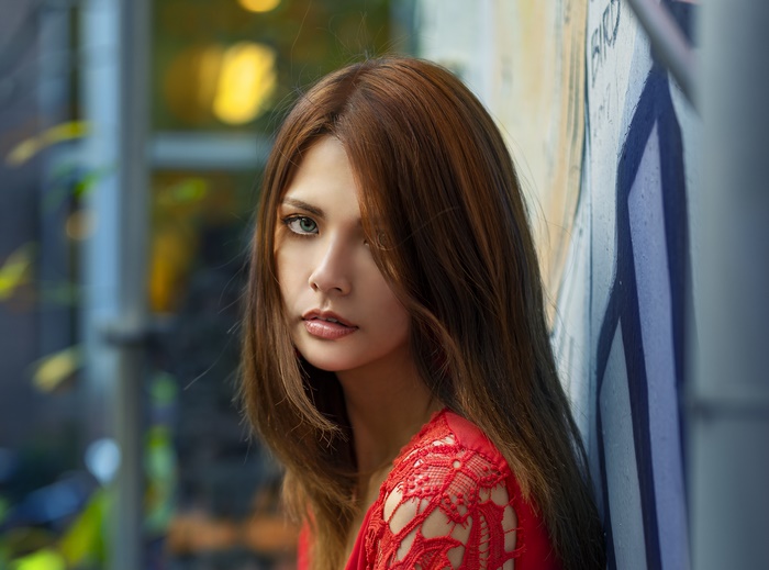 Woman in red lace dress leaning against graffiti wall