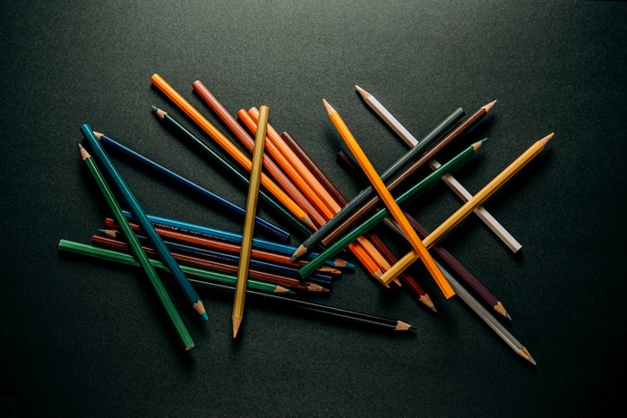 Scattered colored pencils on a dark surface