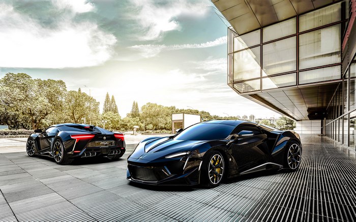 Two black Fenyr SuperSport cars parked outside a modern building
