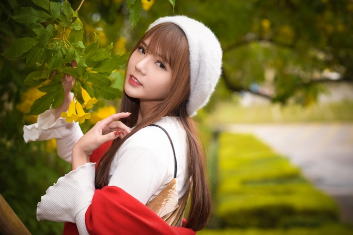 Asian woman with long brown hair wearing a white hat