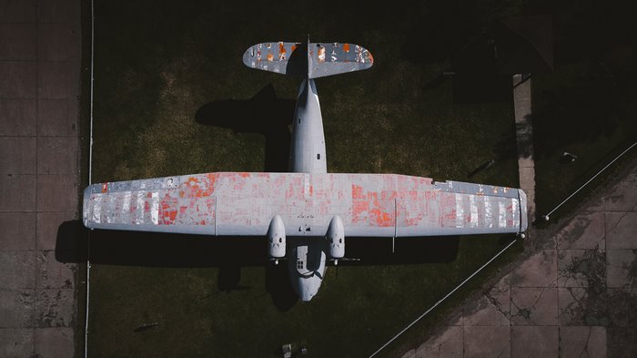 Overhead view of a weathered airplane on grass and concrete