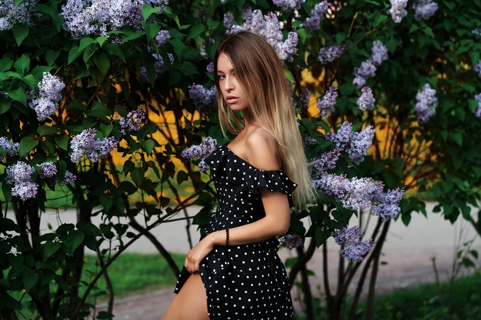 Woman in polka dot dress near lilac bush