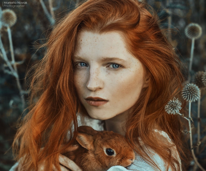 Redhead woman with blue eyes holding a rabbit