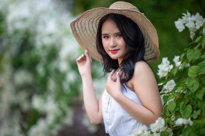 Asian Woman Wearing a Straw Hat with White Flowers