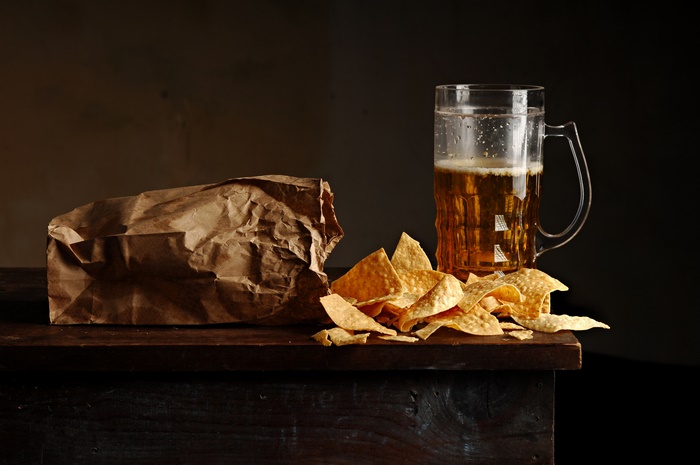 A glass of beer and corn chips