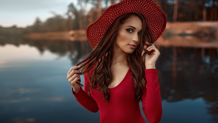 Woman in red hat and dress by the water