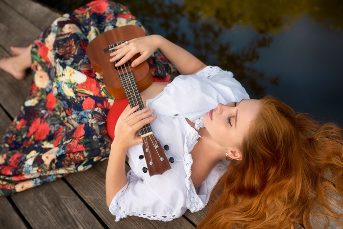 Redhead woman lying down with a ukulele