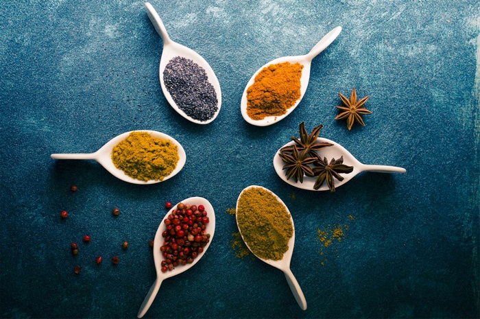 Various spices and herbs arranged on white spoons