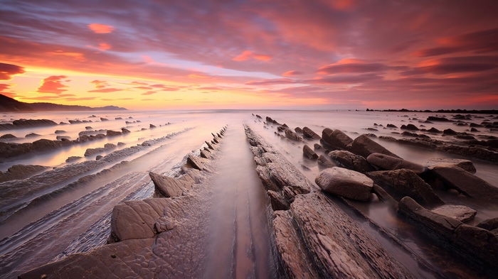 Sunset over rocky beach with dramatic clouds