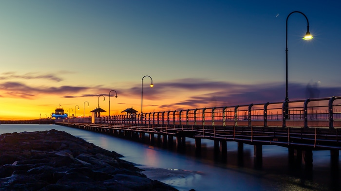 Sunset over a pier with streetlights and ocean