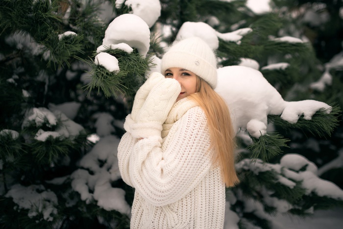 Woman in white winter hat and sweater in snow
