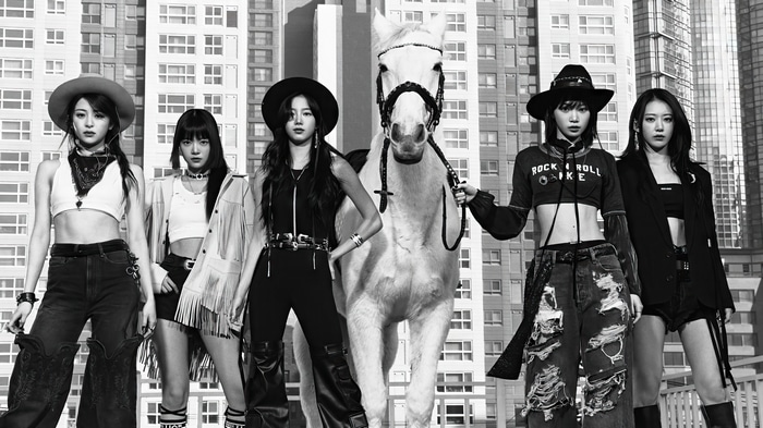 LE SSERAFIM members with a horse in front of buildings