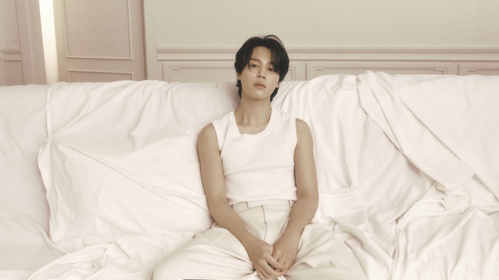 Jimin of BTS sitting on a bed