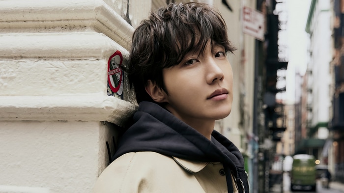 J-Hope of BTS leaning against a building in a city