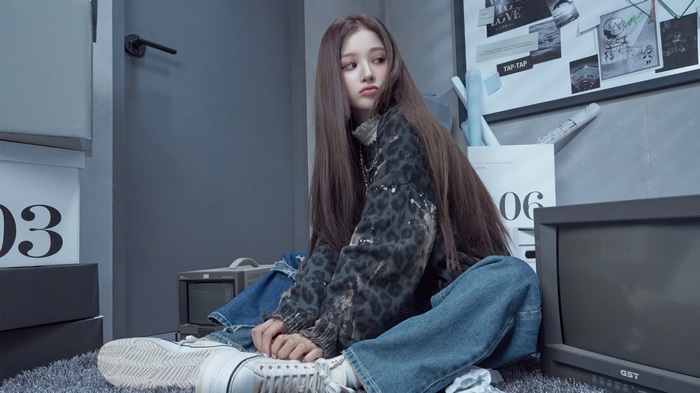 Sullyoon of NMIXX sitting on the floor with vintage electronics