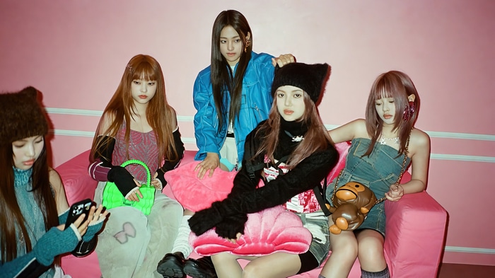 NewJeans members posing on a pink couch