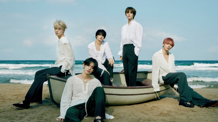 TXT members in a boat on the beach
