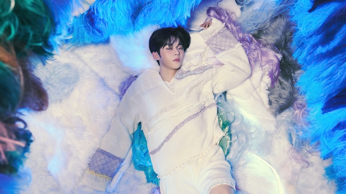 Yeonjun of TXT lying on fluffy blue and white material