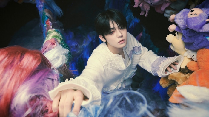 Yeonjun of TXT surrounded by plush toys and colorful hair