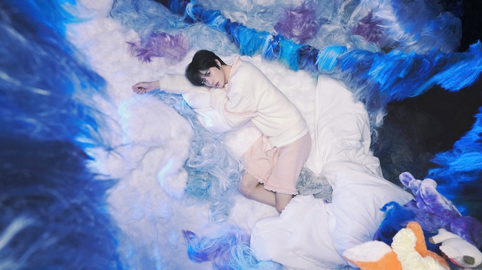 TXT Beomgyu sleeping on a bed of colorful fluff
