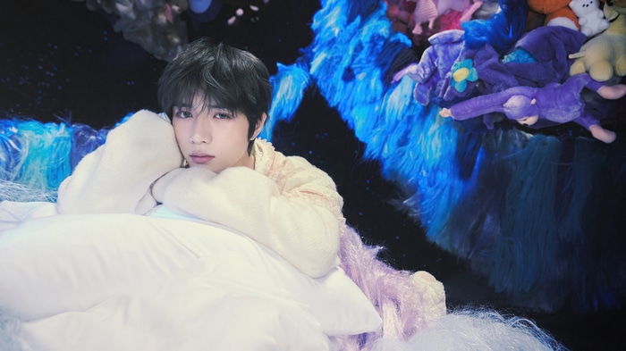 Beomgyu of TXT lying on pillows with plush toys