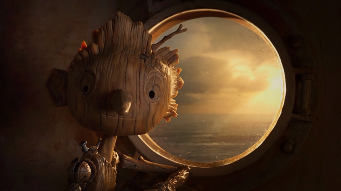 Pinocchio looking out a porthole at sunset