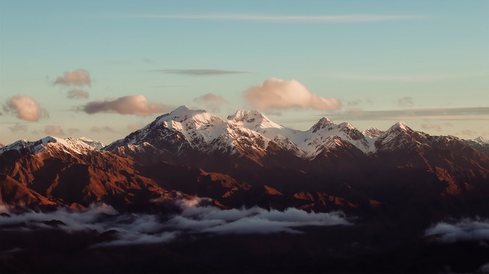 Snow-capped mountains at sunset with clouds