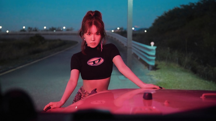 Wendy from Red Velvet leans on a car at night