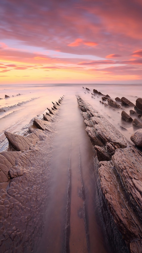 Sunset over rocky beach with misty water