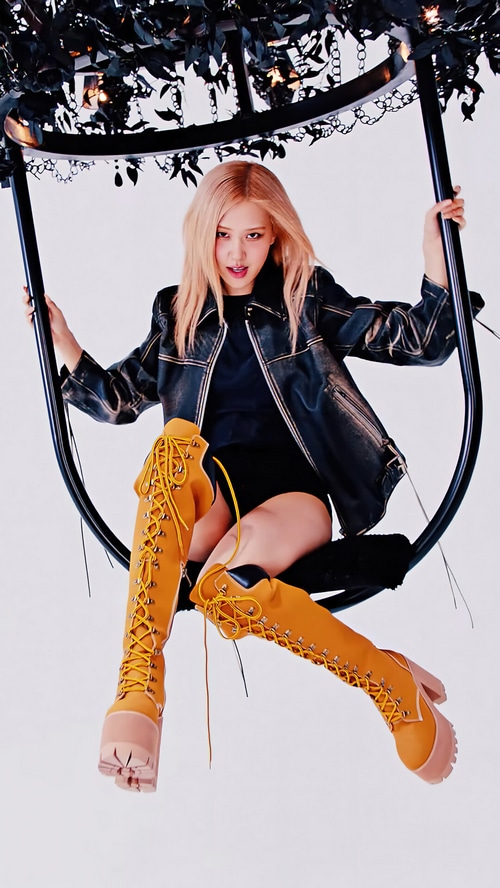 Rosé of BLACKPINK sits on a swing wearing a leather jacket and boots