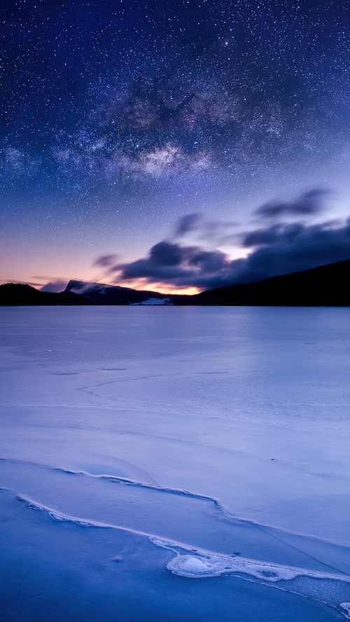 Milky Way over a frozen lake in Switzerland at sunrise