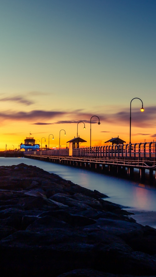 Sunset over a pier with streetlights and ocean