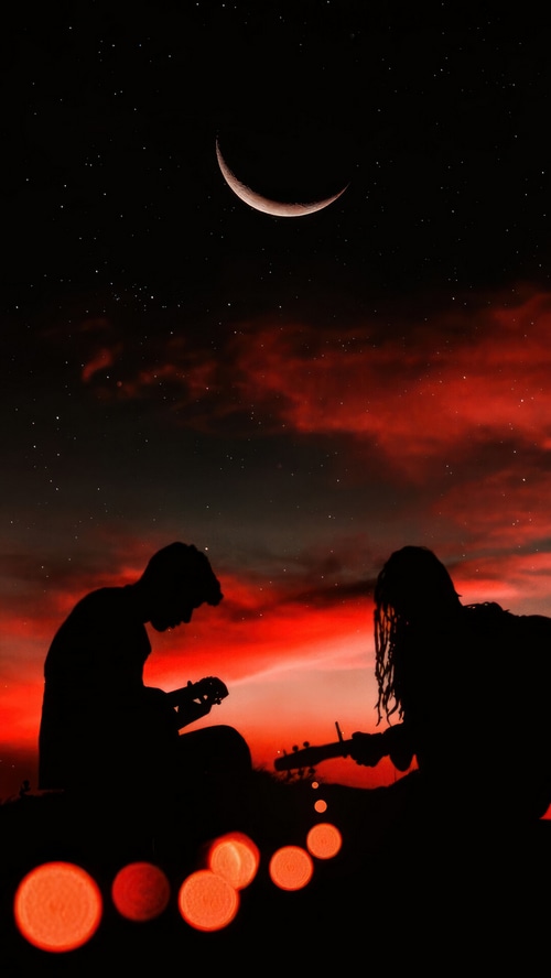 Two people playing guitar under a crescent moon